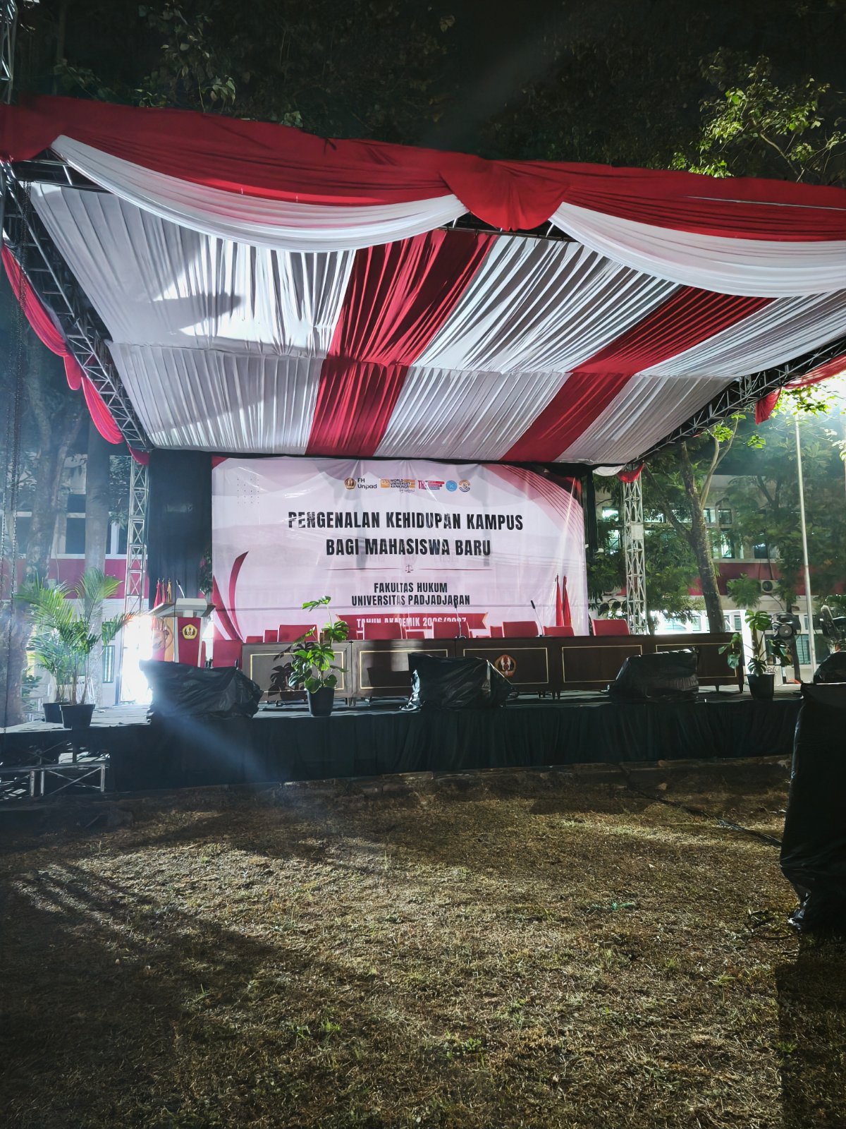 Panggung rigging dengan dekorasi kain merah putih dan backdrop untuk acara kampus