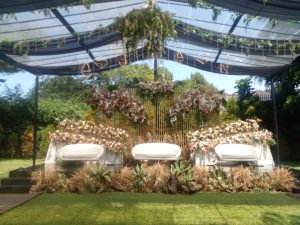 Pelaminan garden party di bawah tenda transparan dengan kain hitam